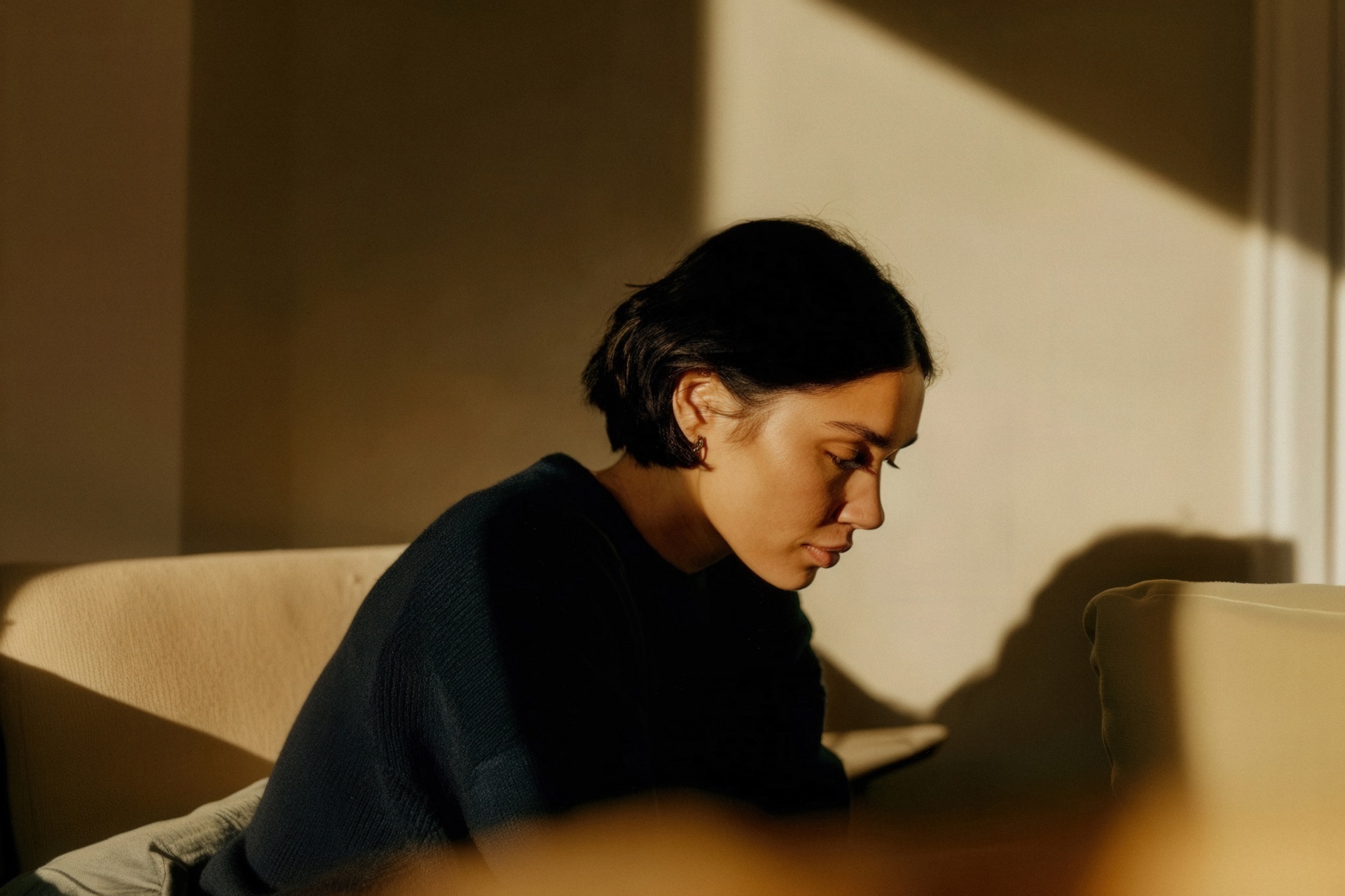 A woman on a sofa in late afternoon light, reading