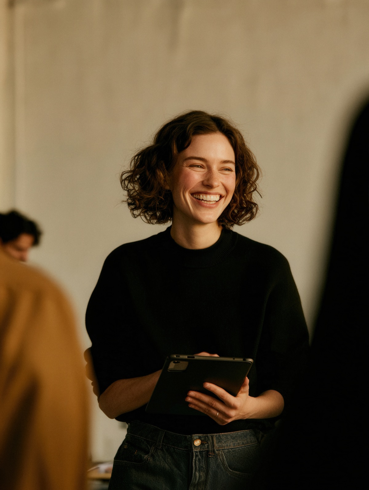 A woman smiling, holding a tablet